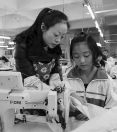 大英縣中等職業技術學校內，企業服裝技師正指導學生進行縫紉操作。